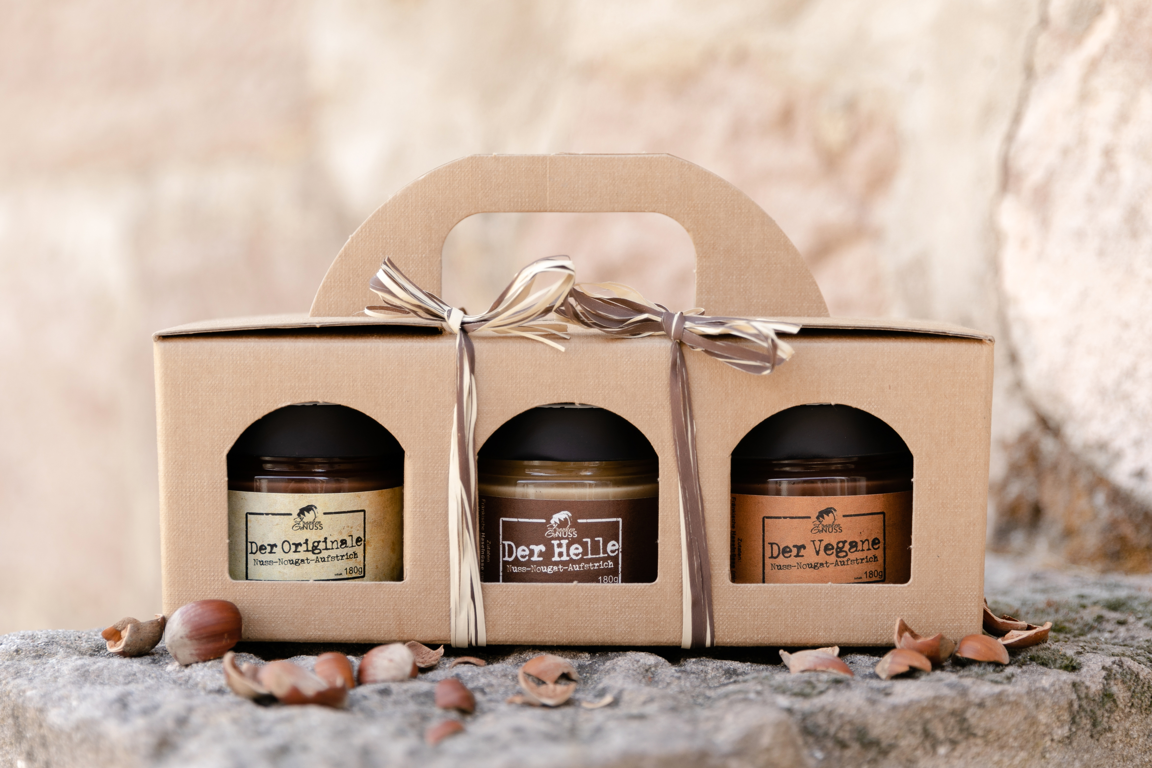 Die Geschenkbox „Dreierlei“ präsentiert drei Gläser Nuss-Nougat-Aufstrich in einer dekorativen Kartonage. Die Geschenkbox „Dreierlei“ präsentiert drei Gläser Nuss-Nougat-Aufstrich in einer dekorativen Kartonage.