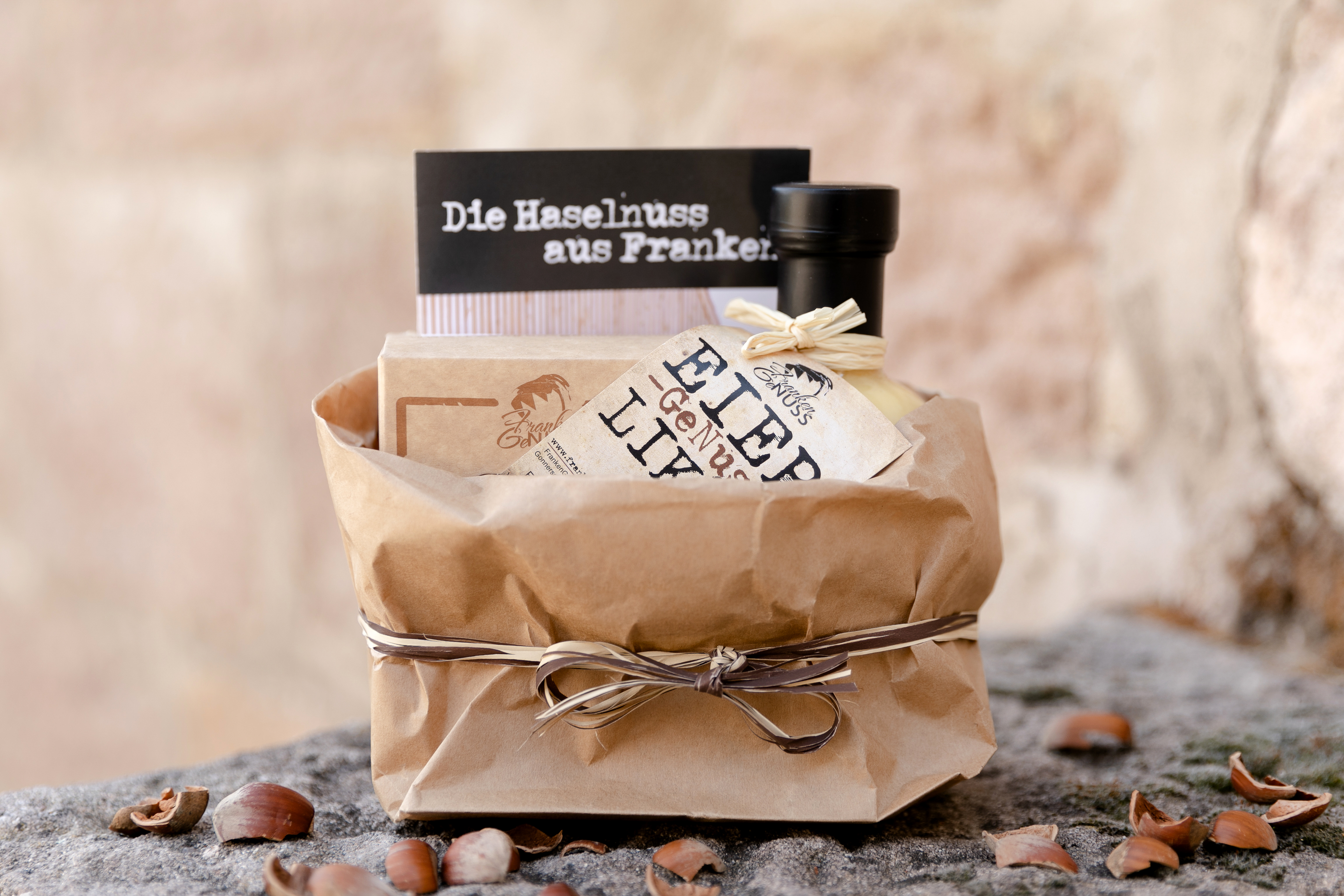 Das kleine, aber feine GeNuss-Geschenk in einer rustikalen Papiertüte, umgeben von frischen Haselnüssen.