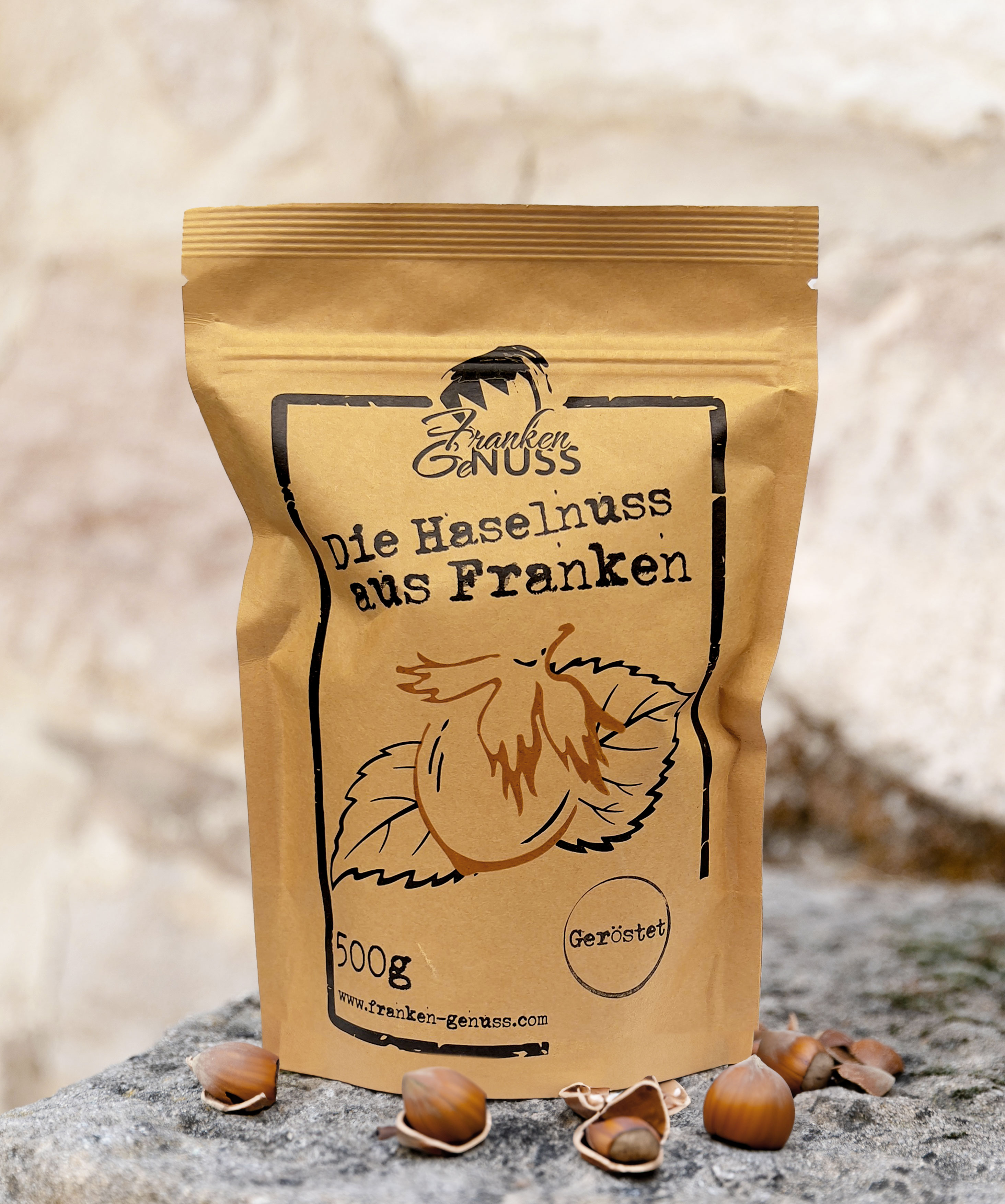 Eine braune Verpackung mit Haselnüssen liegt auf einem steinigen Untergrund.