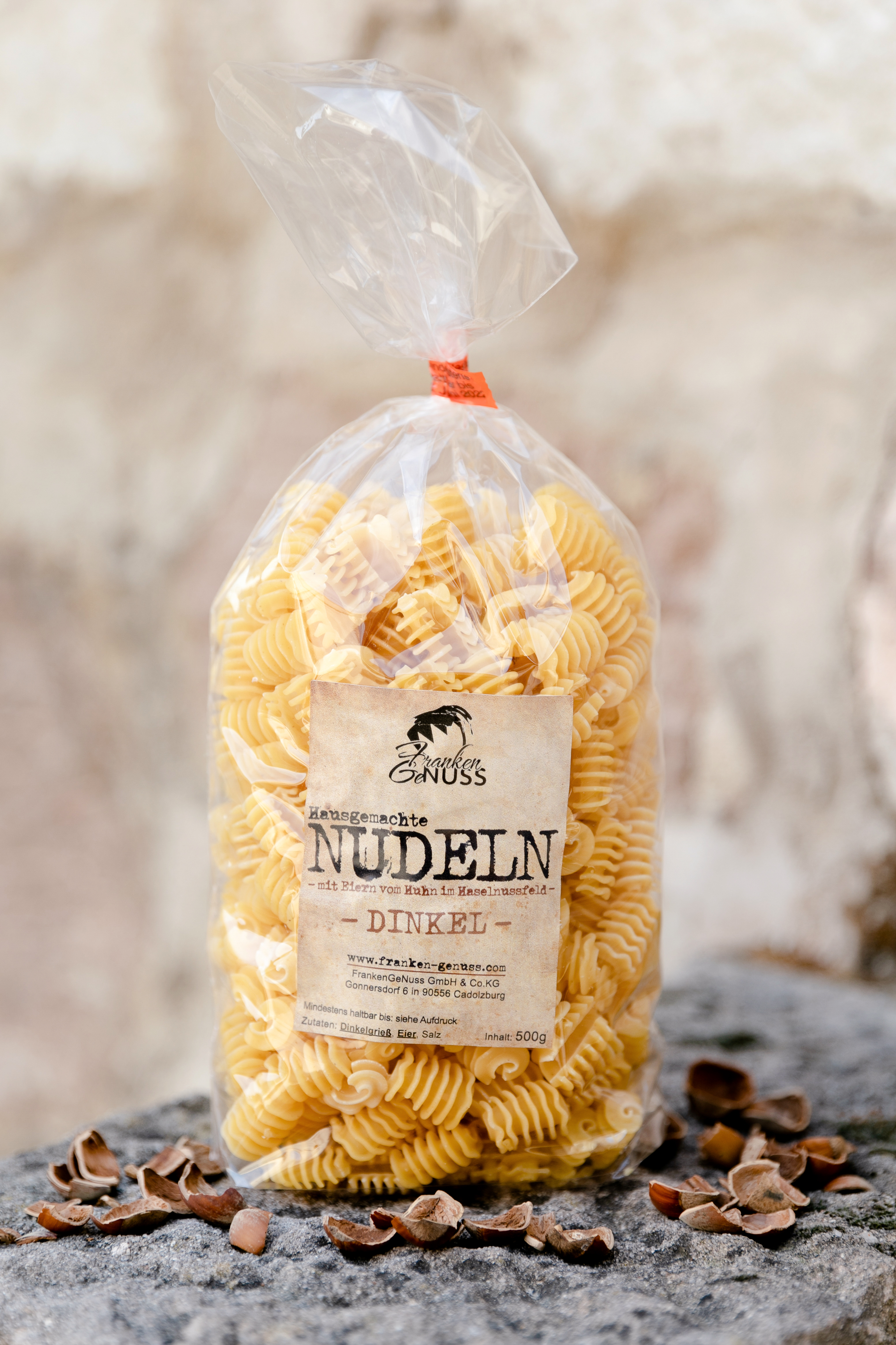 Goldgelbe, spiralförmige Dinkel Eiernudeln auf einem steinernen Untergrund, umgeben von Nussschalen. Goldgelbe, spiralförmige Dinkel Eiernudeln auf einem steinernen Untergrund, umgeben von Nussschalen.