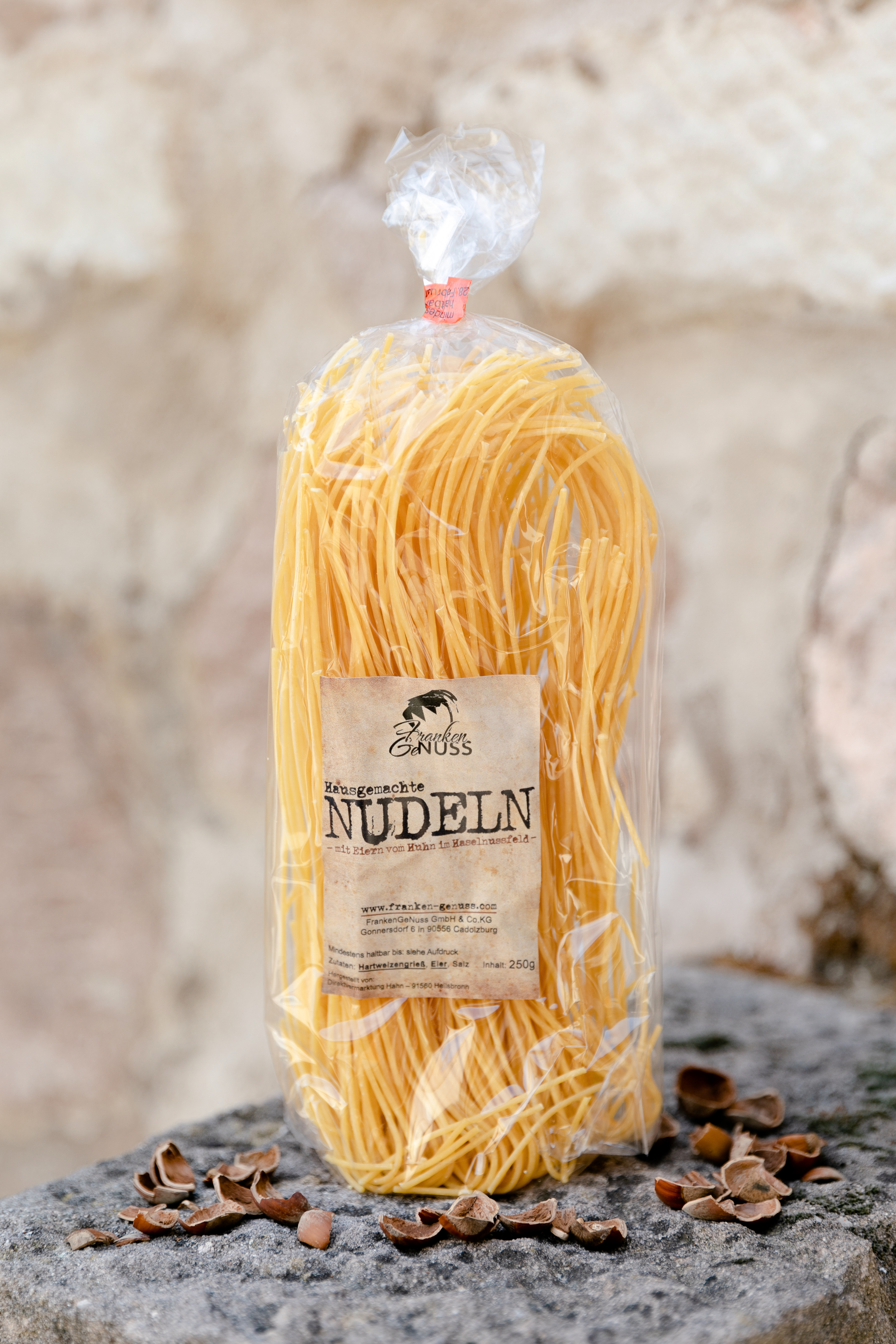Goldgelbe Eiernudeln als Spaghetti auf einem steinernen Untergrund mit verstreuten Nussschalen. Goldgelbe Eiernudeln als Spaghetti auf einem steinernen Untergrund mit verstreuten Nussschalen.