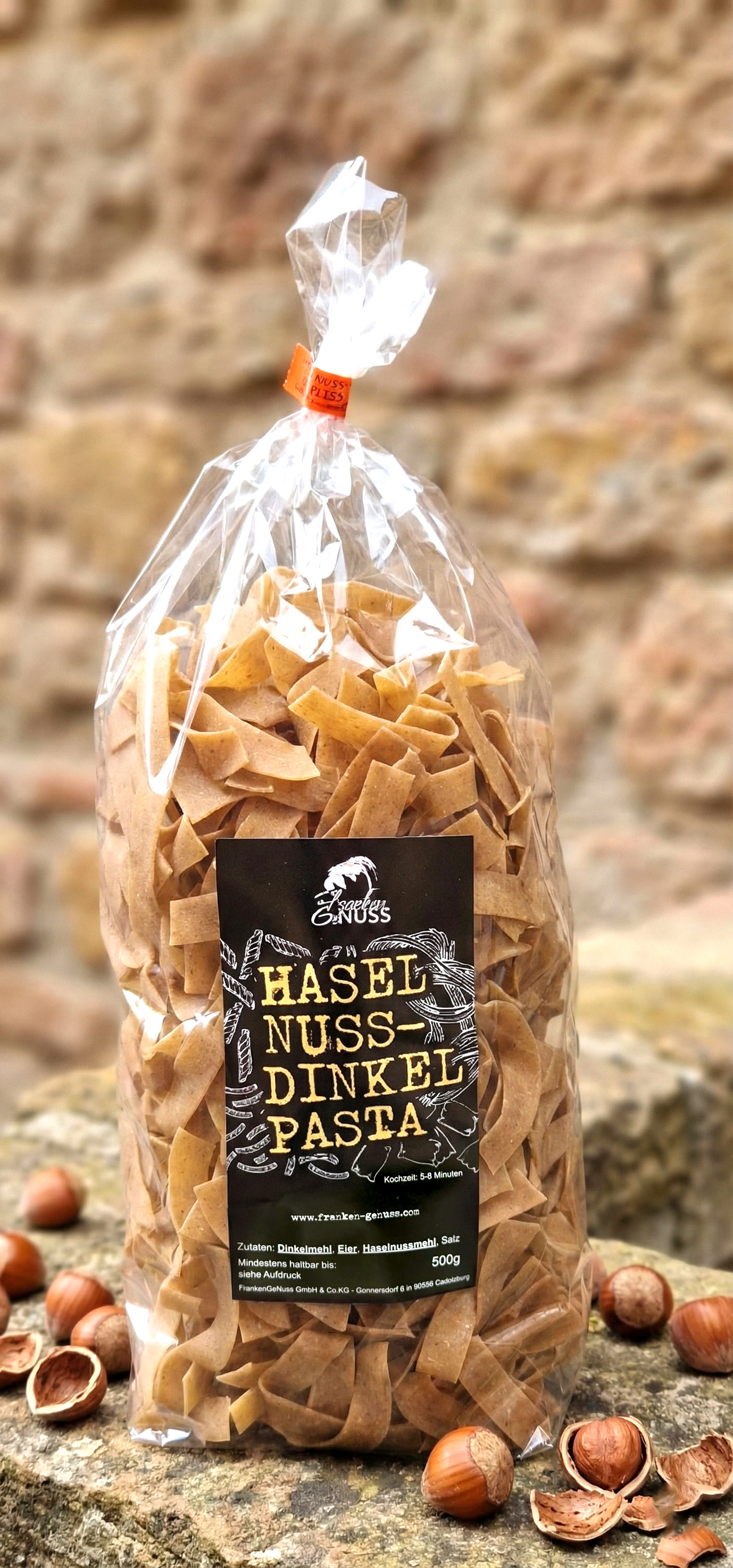 Feine Haselnuss-Dinkel-Nudeln umgeben von ganzen Haselnüssen auf rustikalem Naturstein. Feine Haselnuss-Dinkel-Nudeln umgeben von ganzen Haselnüssen auf rustikalem Naturstein.